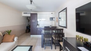 Un espace de vie compact comprenant un coin cuisine, un coin repas et un espace détente avec un canapé et des fauteuils.