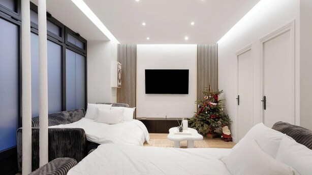 Quarto moderno com duas camas, uma televisão e um pinheiro de Natal.