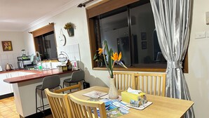 Une cuisine avec un plan de travail en bois, un évier et une fenêtre donnant sur un beau paysage. On y trouve une table à manger avec des chaises et un vase rempli de fleurs.