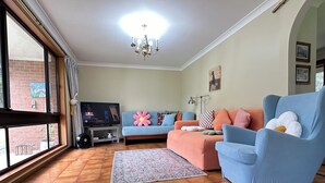 Un salon avec un téléviseur, des canapés et un tapis.