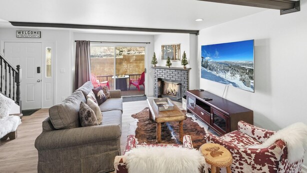 A living room with a fireplace, a sofa, a coffee table, and a television. - Ski In Ski Out Condo at Bear Mountain! HOT TUB! Walk Onto Chair Lift 9! (Big Bear Lake)