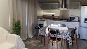 Eine kompakte Küche mit Essbereich, einem kleinen Tisch und einer Couch.