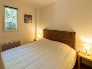 Un dormitorio con cama, dos lámparas de noche, un radiador, una ventana con vistas y un cartel en la pared.