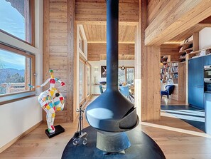A modern interior with a large black stove, wooden walls, and a view of the outdoors. - Larch chalet - Les Gets - La Massouderie (Les Gets)