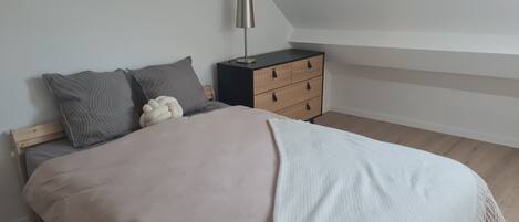 A bedroom with a bed, pillows, a bedside table, and a lamp.