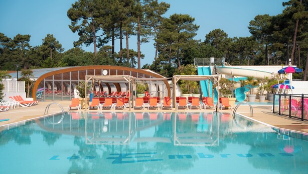 Une piscine avec des chaises longues et un espace de repos abrité.