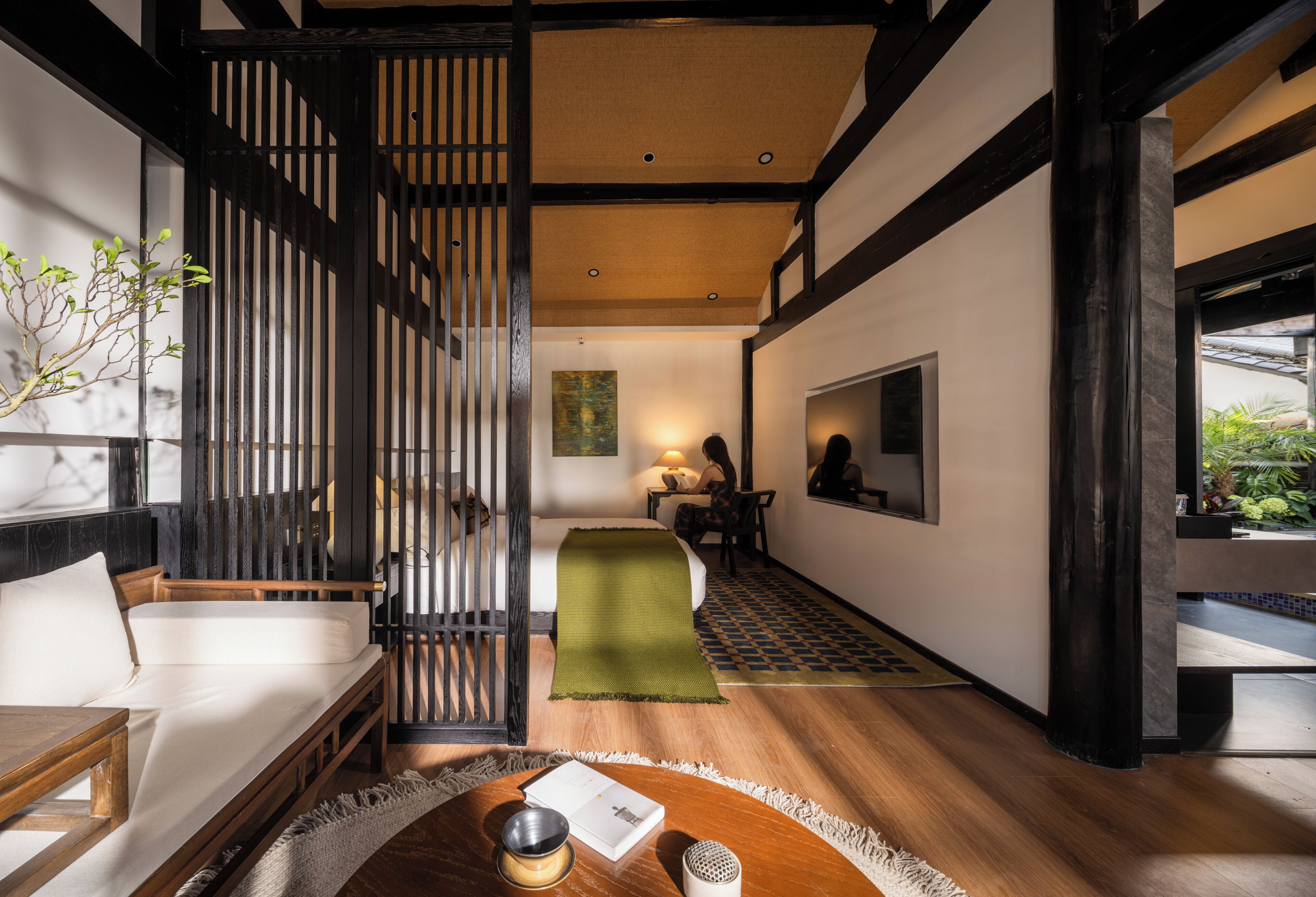 A traditional Japanese-style room with tatami flooring, a low table with a bowl and book, a sofa, and a sliding door.