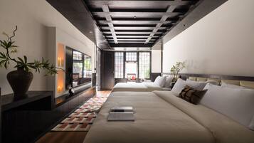 Un hotel moderno con una cama grande, televisión, planta en maceta y vistas al exterior.