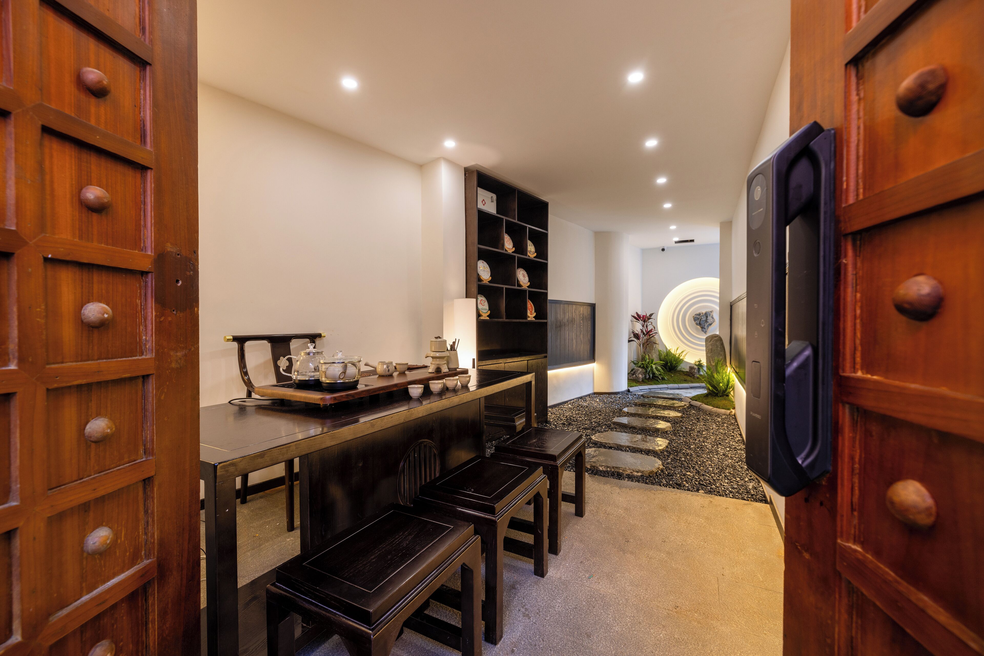 Ein traditioneller japanischer Raum mit Tatami-Boden, einem niedrigen Tisch mit Teeset und einer Holzkabine mit Dekorationen.