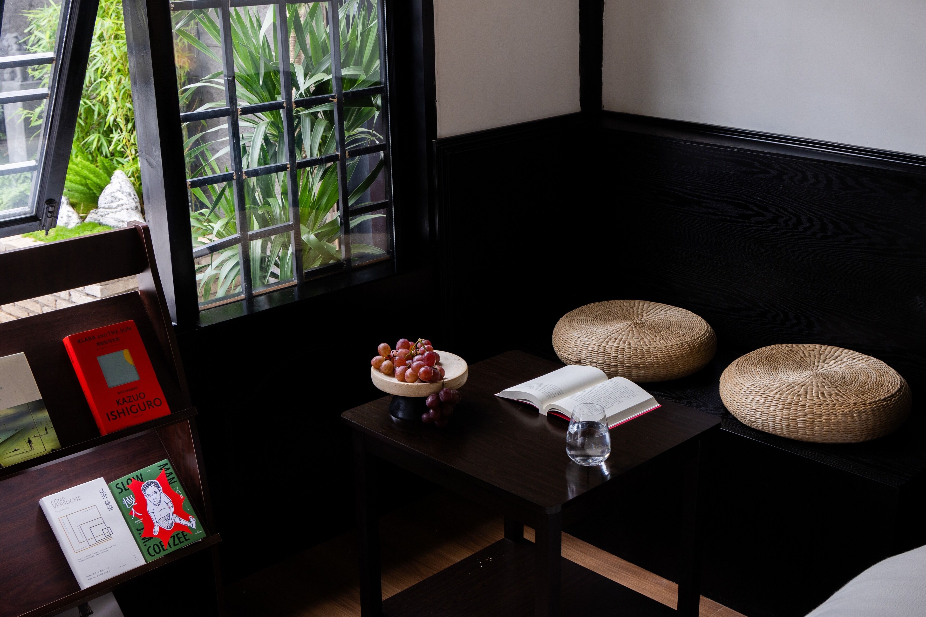 A reading area with a table, a bowl of grapes, a book, and a glass of water.