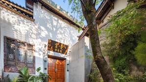 A traditional building with a wooden door, a sign with Chinese characters, and a staircase leading to the entrance.