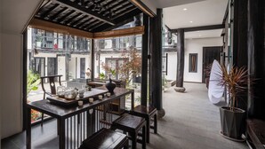A traditional Japanese-style room with tatami flooring, a low table with a tea set, and a view of the outside garden.
