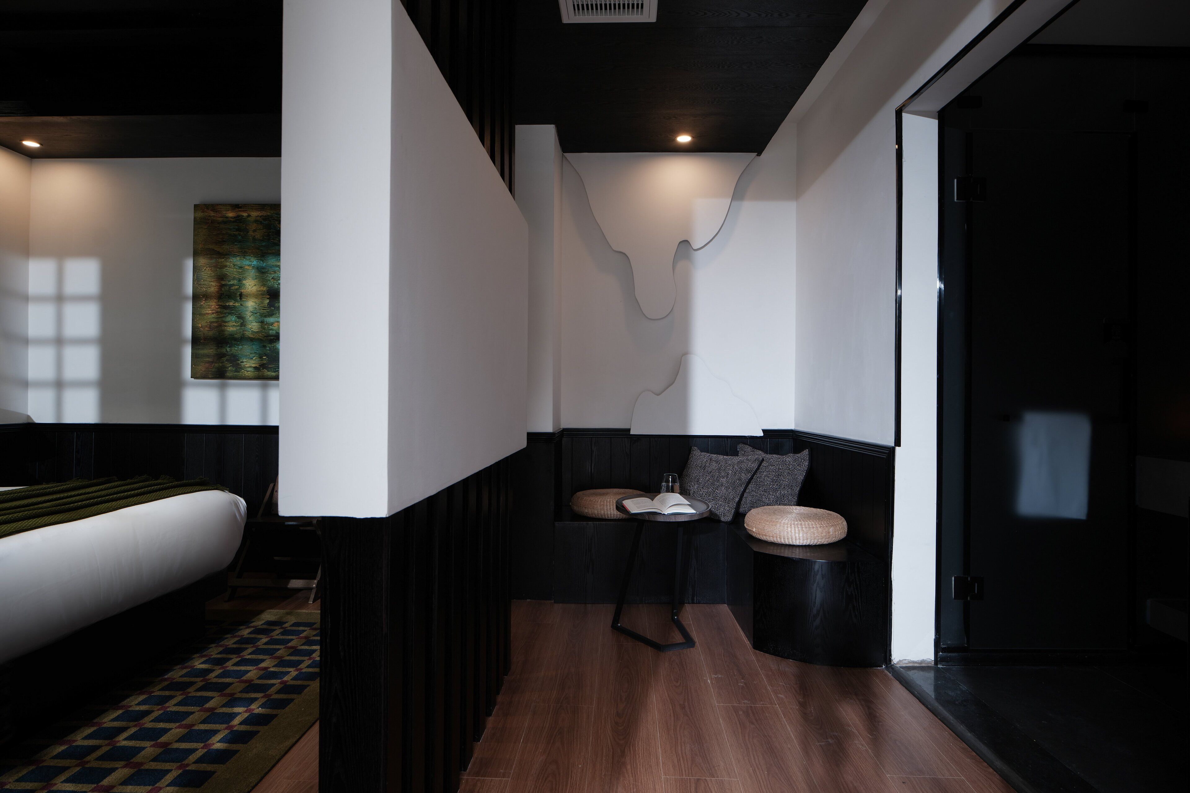 Quarto de hotel moderno com uma cama grande, um espaço de estar pequeno com almofadas e um design de parede exclusivo.