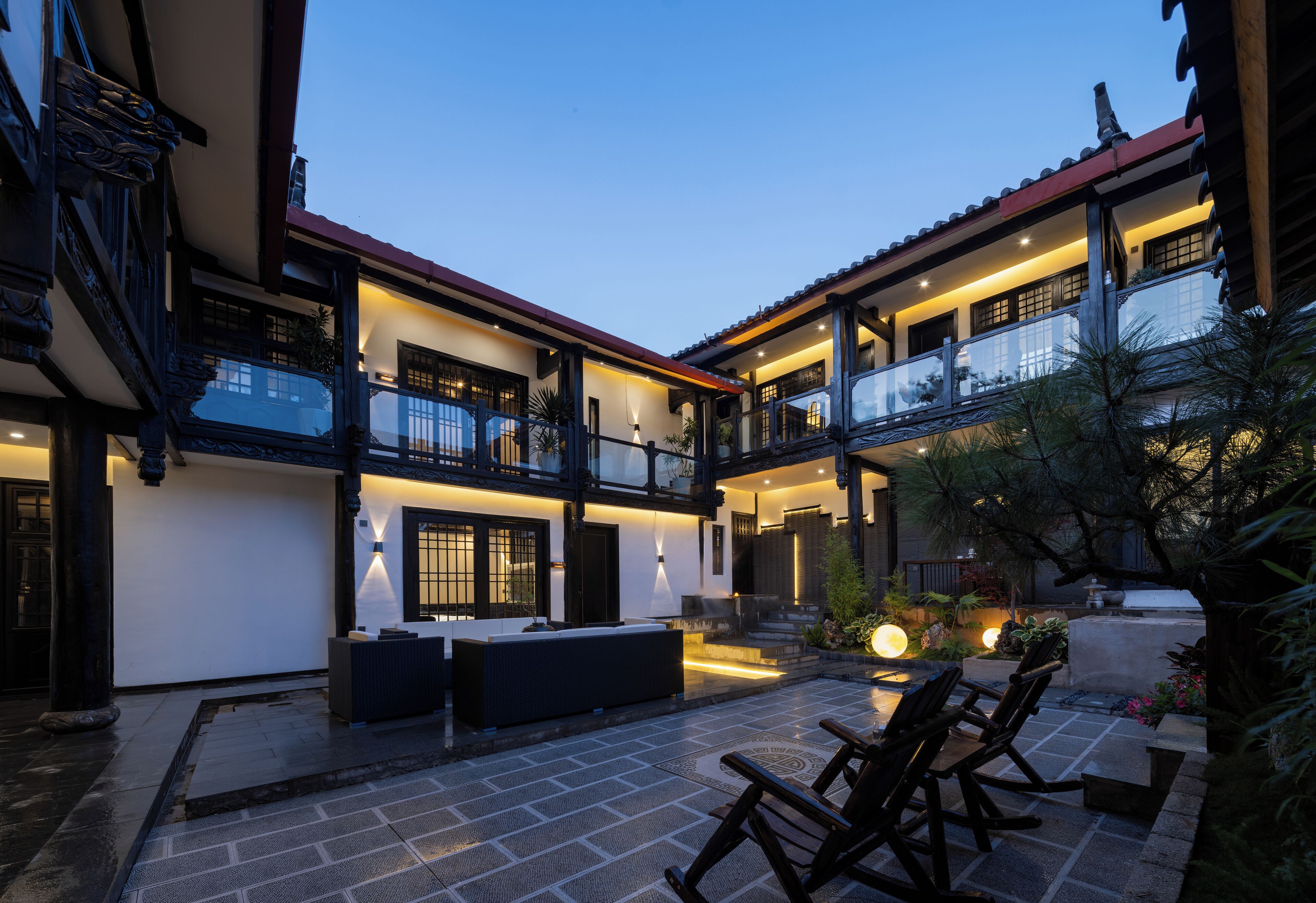 A two-story building with a balcony, outdoor seating area, and a well-lit patio.