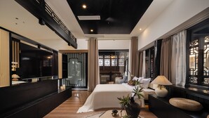 A modern hotel room with a large bed, a desk, a TV, and a balcony.