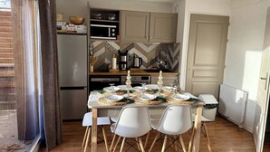 A compact kitchen with modern appliances, a dining table set for four, and a view of the outside. - Le Refuge du Loup - Panoramic view, Netflix & Pool (Dévoluy)