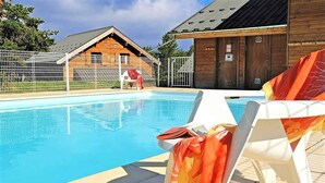 A swimming pool with lounge chairs and a wooden building in the background. - Le Refuge du Loup - Panoramic view, Netflix & Pool (Dévoluy)