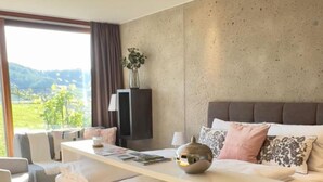 A modern bedroom with a bed, bedside table, and a view of the outdoors. - At home in the location with pool in beautiful surroundings (Graßnitzberg)