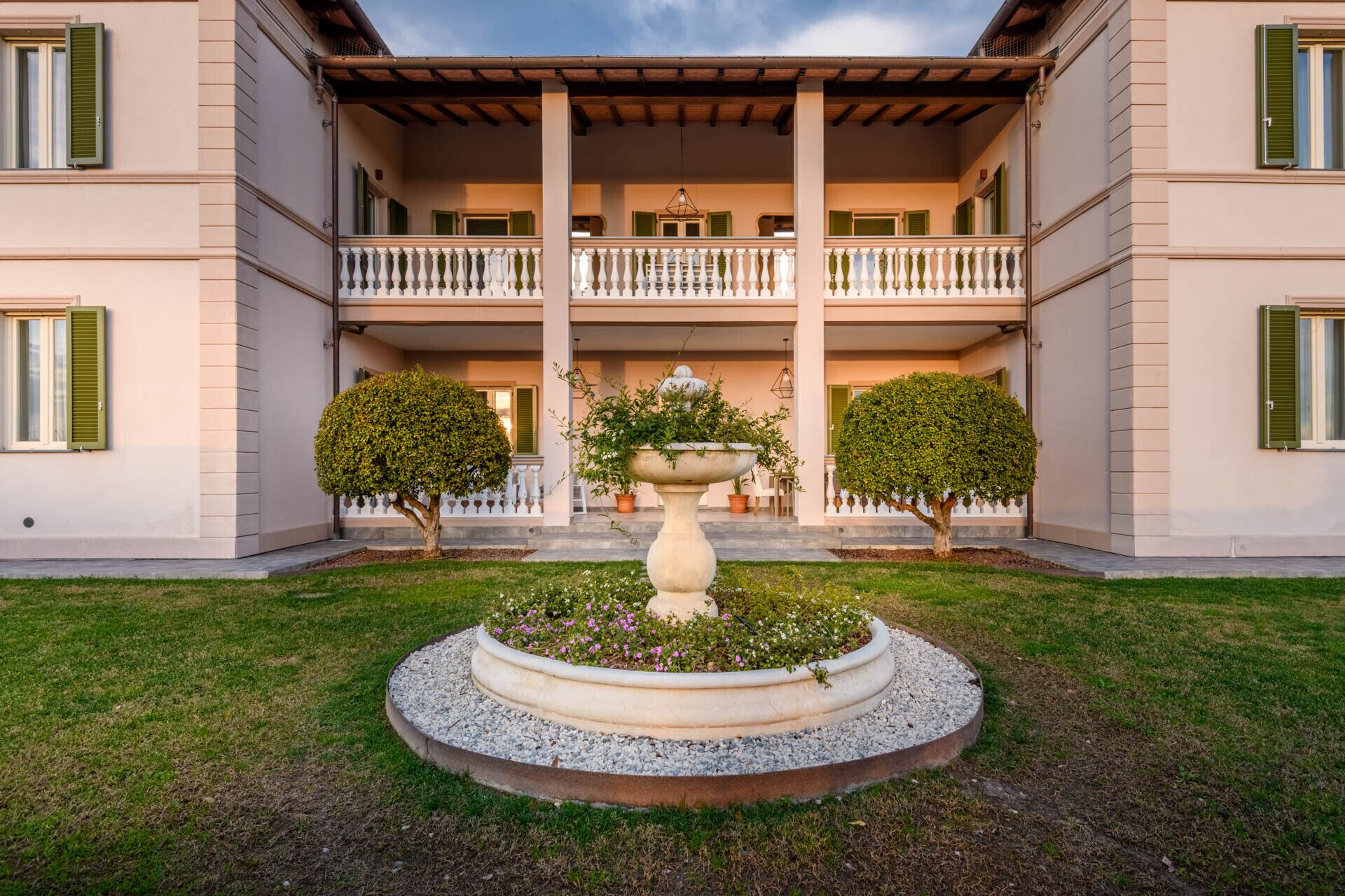 Un bâtiment doté d’une cour intérieure, d’une fontaine et de deux arbres disposés de manière symétrique.