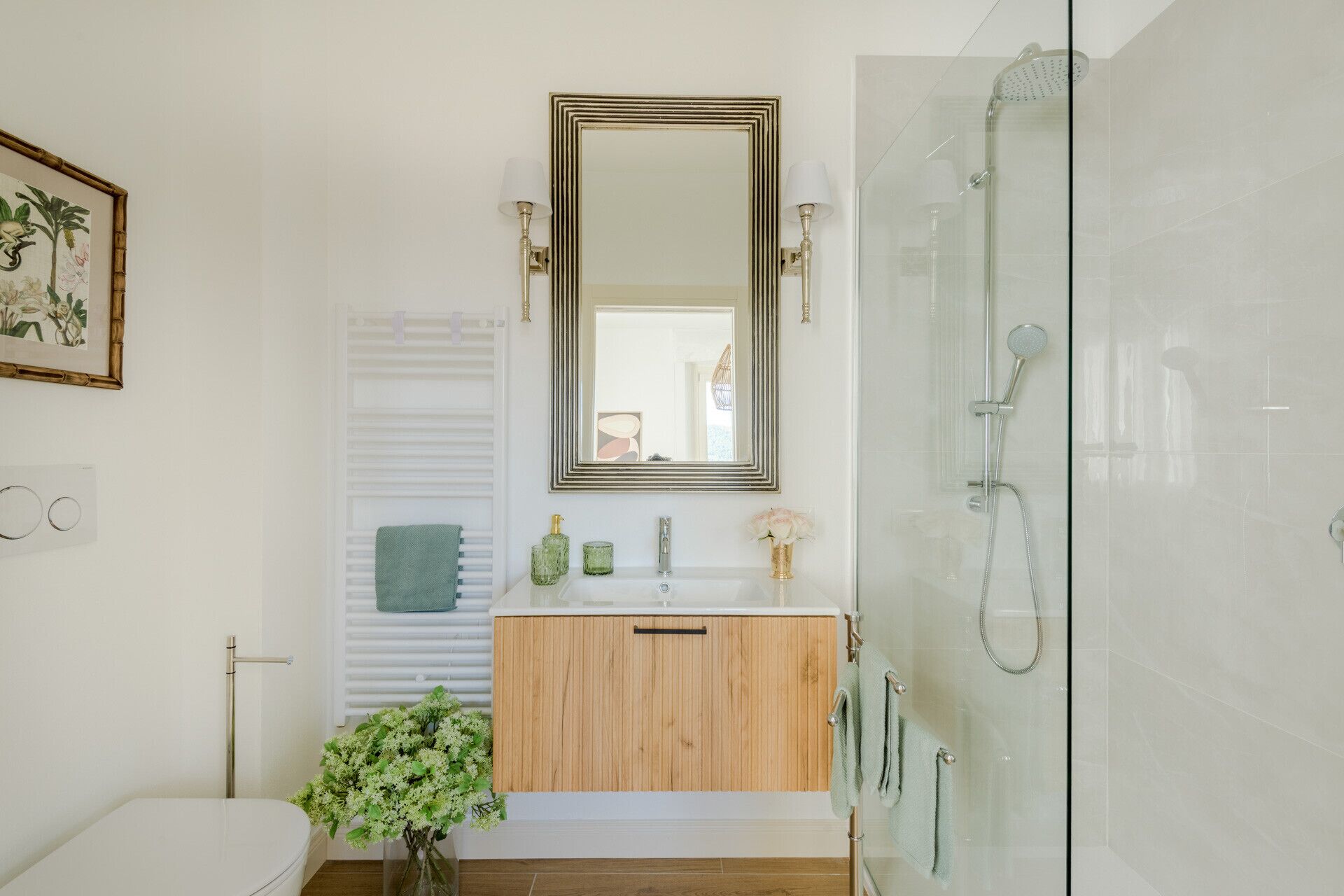 Une salle de bain avec une douche à parois de verre, un meuble-lavabo en bois, un lavabo blanc et un grand miroir.