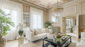 A luxurious living room with a white sofa, a black coffee table, and a chandelier. - The Marble Penthouse (Lucca)