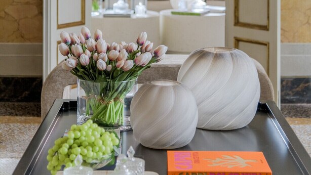 A luxurious interior with a chandelier, a vase of flowers, and a book on a table. - The Marble Penthouse (Lucca)