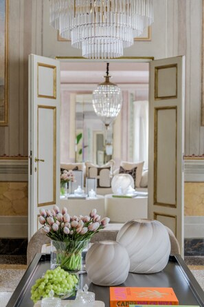 A luxurious interior with a chandelier, a vase of flowers, and a book on a table. - The Marble Penthouse (Lucca)