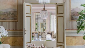 A luxurious room with a grand chandelier, a view of a mountainous landscape through a large window, and elegant furnishings. - The Marble Penthouse (Lucca)