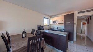 A modern kitchen with a central island, a dining table with chairs, and a small window. - nice Apt for 6 pers near the Marina (Mandelieu-la-Napoule)