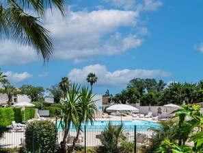 A pool area with lounge chairs and umbrellas, surrounded by palm trees and greenery. - Nice apart for 4pers, close to the marina (Mandelieu-la-Napoule)
