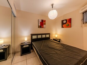 A bedroom with a bed, bedside tables, a hanging light fixture, and two wall art pieces. - Nice apart for 4pers, close to the marina (Mandelieu-la-Napoule)