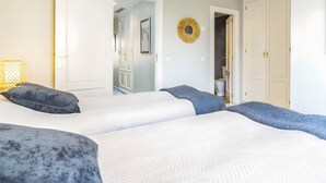 A bedroom with a large bed, two doors, a hallway, and a small trash can. - Holiday Home 'Fantastic Townhouse Aloha Na' with Mountain View, Wi-Fi and Air Conditioning (Marbella)