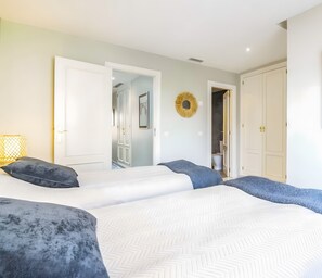 A bedroom with a large bed, two doors, a hallway, and a small trash can. - Holiday Home 'Fantastic Townhouse Aloha Na' with Mountain View, Wi-Fi and Air Conditioning (Marbella)