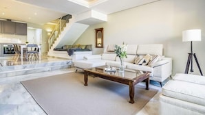 A spacious living area with a white sofa, a coffee table, and a lamp. - Holiday Home 'Fantastic Townhouse Aloha Na' with Mountain View, Wi-Fi and Air Conditioning (Marbella)