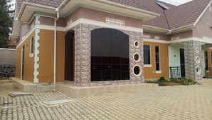 A two-story house with a tiled roof, a large arched entrance, and a paved driveway.