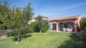 A house with a tiled roof, a patio with outdoor furniture, and a well-maintained lawn. - Air-conditioned house for 6 people with garden and swimming pool near the lake (Homps)