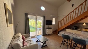 Ein gemütlicher Wohnbereich mit einer Couch, einem Esstisch mit Stühlen, einer Küchenzeile mit Herd und einer Treppe.