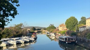 Ein ruhiger Fluss mit anlegenden Booten links und einem Gebäude rechts.