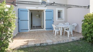 A patio with a table and chairs, a blue door, and a small bench. - South-facing villa for 6 people with a garden and swimming pool (Homps)