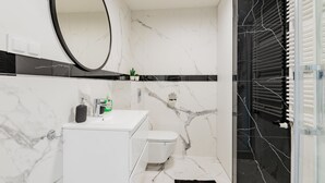 A modern bathroom with a white marble sink, a toilet, and a glass shower enclosure. - Apartamenty Sun & Snow Zwycięzców (Polanica-Zdrój)