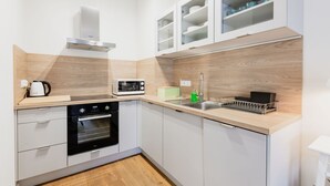 A modern kitchen with a microwave, kettle, oven, and a dish rack. - Apartamenty Sun & Snow Zwycięzców (Polanica-Zdrój)
