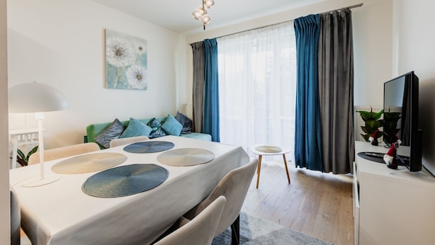 A modern living room with a dining table, sofa, and TV. - Apartamenty Sun & Snow Zwycięzców (Polanica-Zdrój)