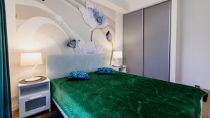 A modern bedroom with a green textured bedspread, two matching pillows, a white headboard, and a decorative wall piece. - Apartamenty Sun & Snow Zwycięzców (Polanica-Zdrój)