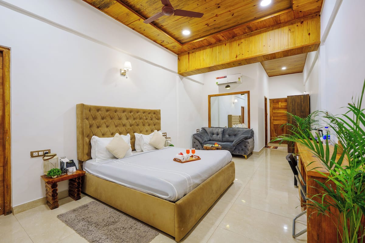 Une chambre avec un grand lit, un plafond en bois, une petite table avec un plateau et un miroir.