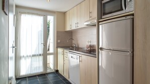 Una cocina moderna con armarios de madera, microondas integrado y refrigerador de acero inoxidable.
