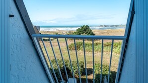 Un balcón con vista al mar y una zona verde.