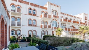 A building with multiple balconies, arched windows, and a courtyard with a table and chairs. - Nice Apt 5 pers near the beach with pool (La Tranche-sur-Mer)