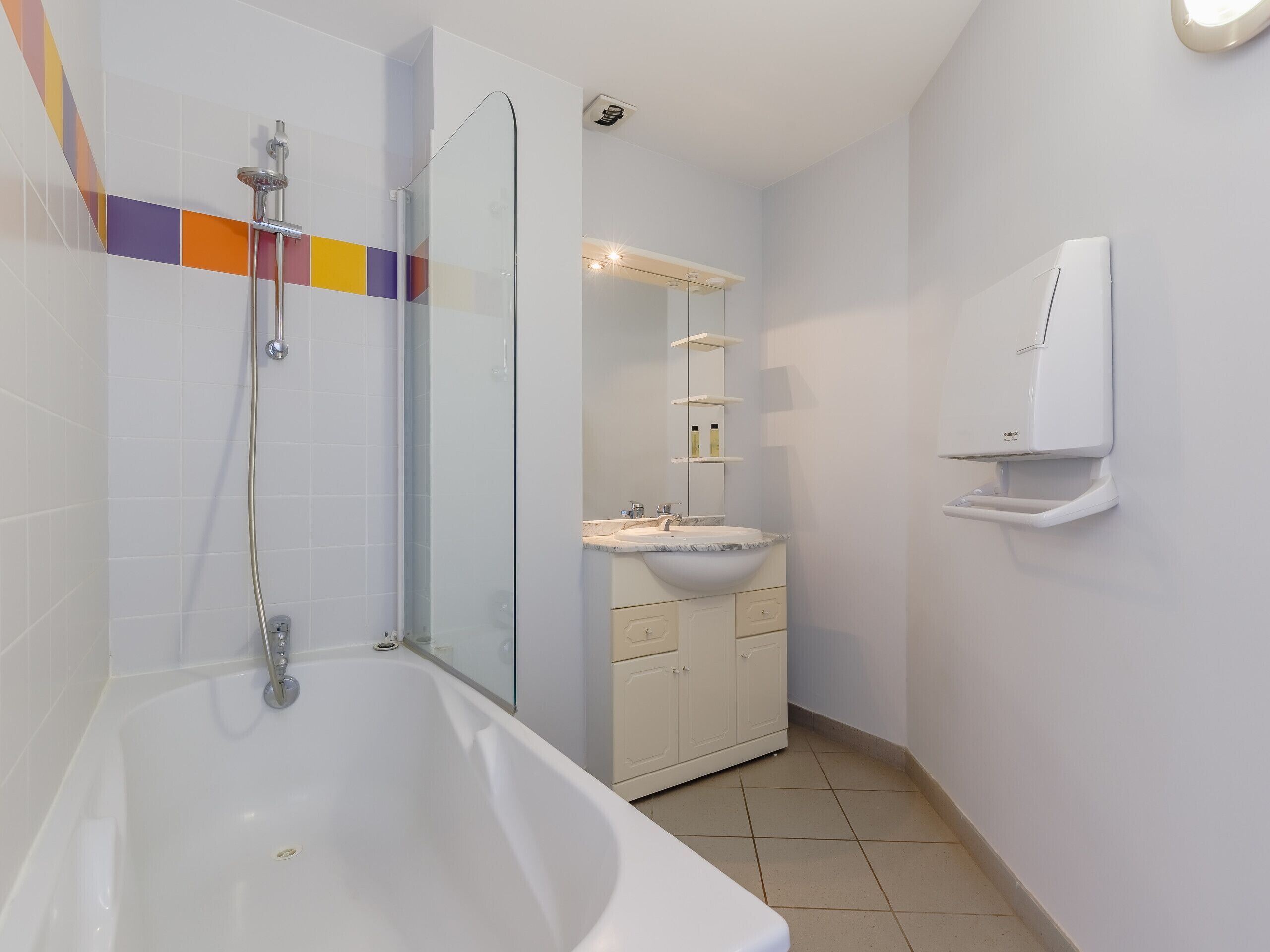 A modern bathroom with a bathtub, a glass-enclosed shower, a white sink, and a mirror.