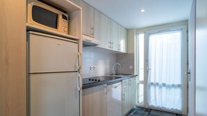 A compact kitchen with a microwave, refrigerator, stove, and sink.