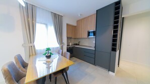 Een moderne keuken met een eettafel, stoelen en een kleine potplant.